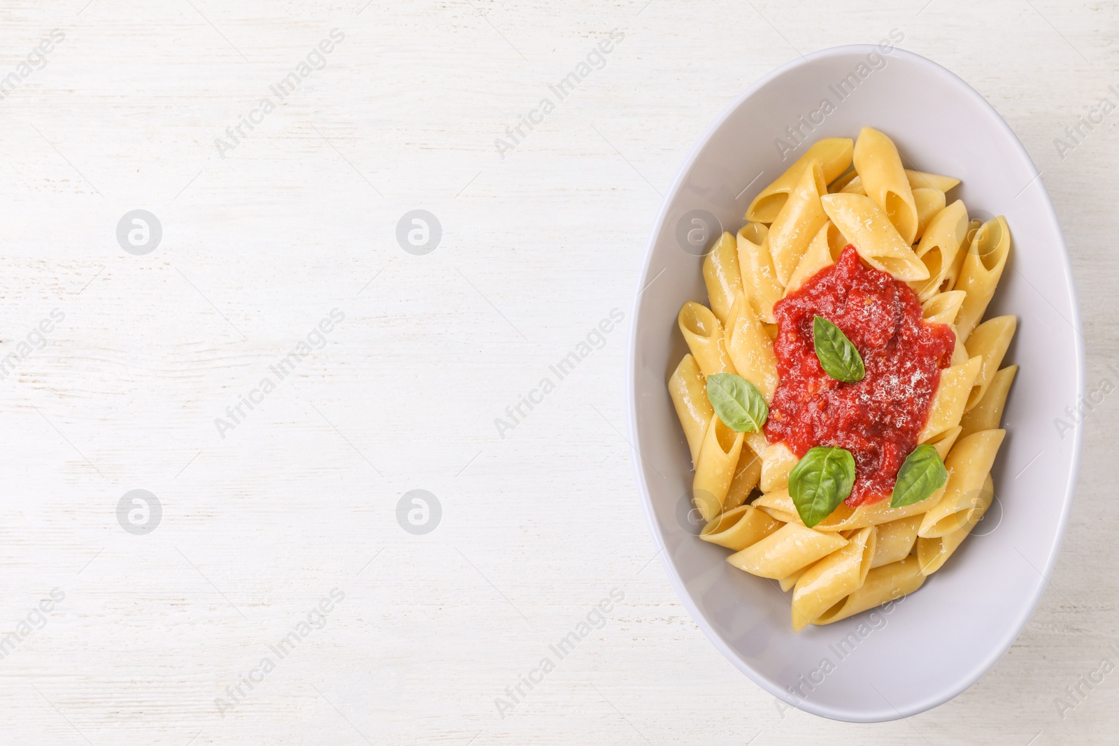 Photo of Tasty pasta with tomato sauce, basil and cheese on white wooden table, top view. Space for text