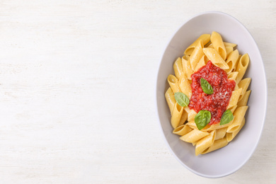 Tasty pasta with tomato sauce, basil and cheese on white wooden table, top view. Space for text