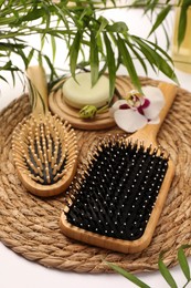 Photo of Wooden hairbrushes, solid shampoo, orchid flowers and leaves on white background