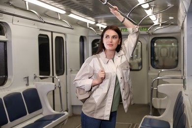 Photo of Beautiful woman with backpack in subway train. Public transport