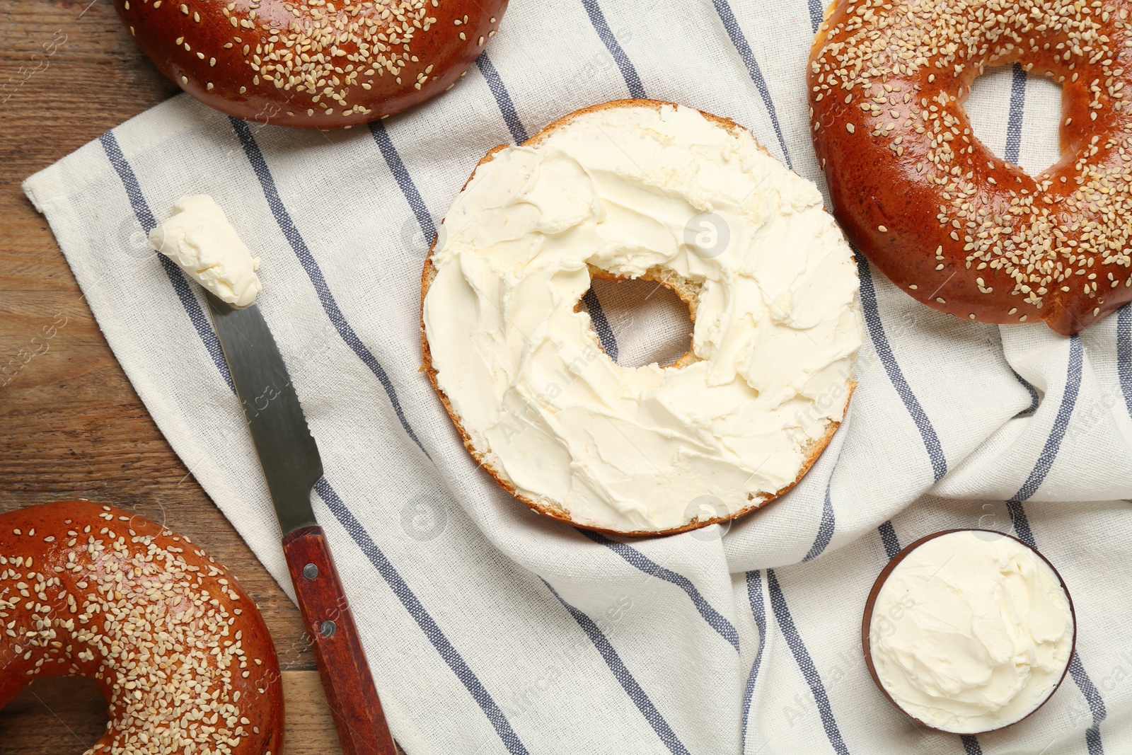 Photo of Delicious bagel with cream cheese on table, flat lay