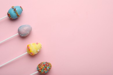 Photo of Egg shaped cake pops and space for text on pink background, flat lay. Easter celebration