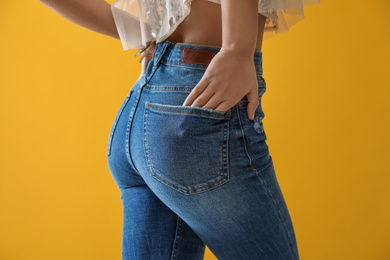 Photo of Woman wearing jeans on yellow background, closeup