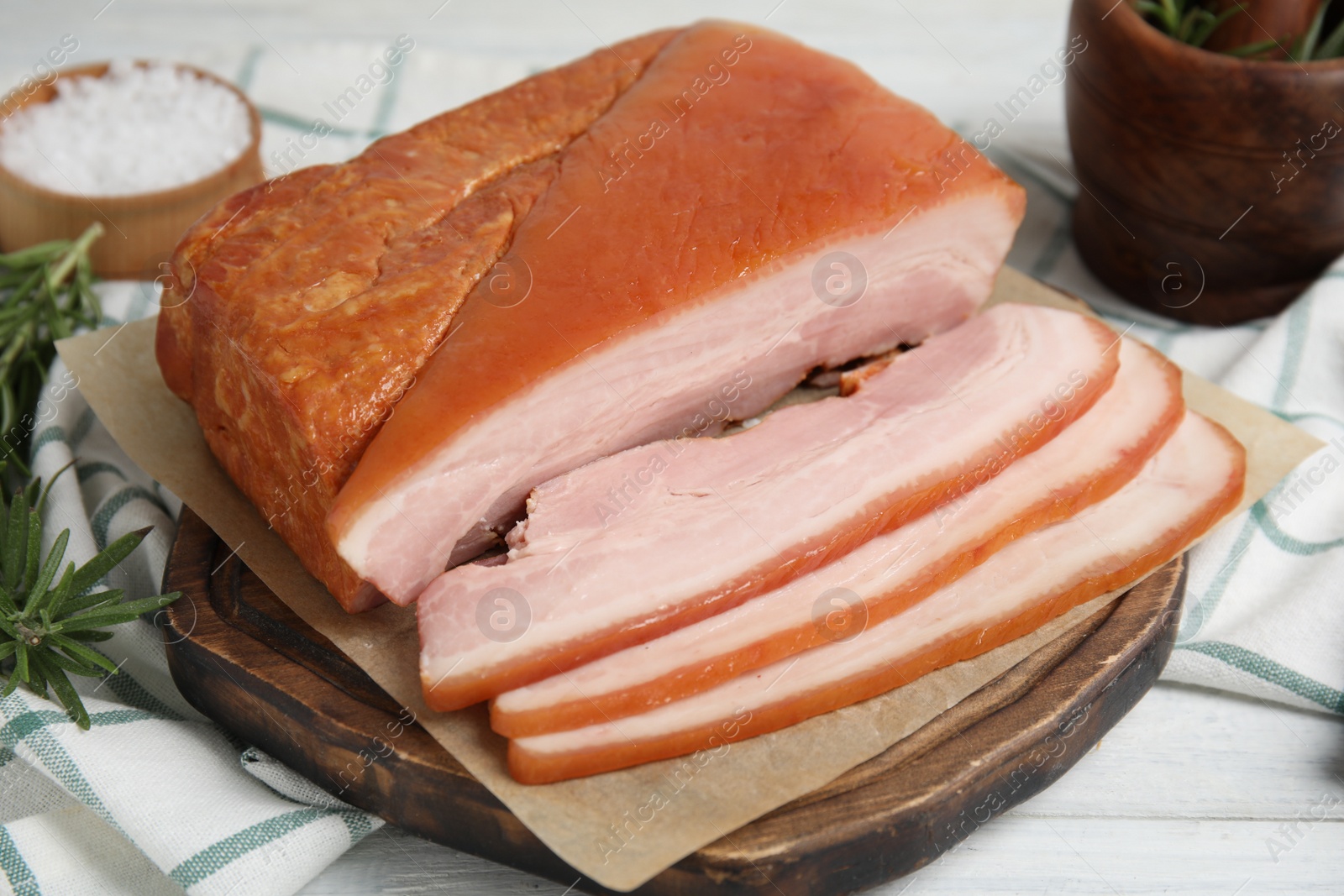 Photo of Delicious smoked bacon on white wooden table, closeup