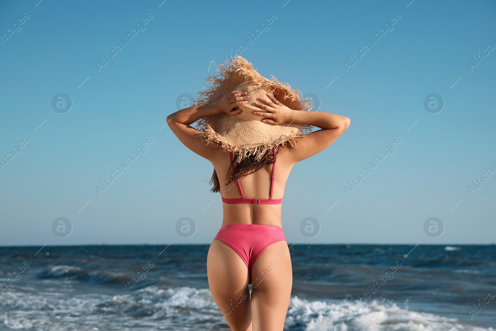 Photo of Young woman with attractive body on beach, back view