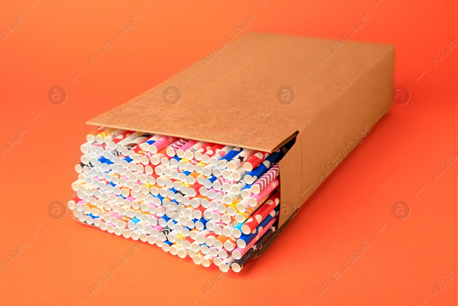 Photo of Box with many paper drinking straws on orange background