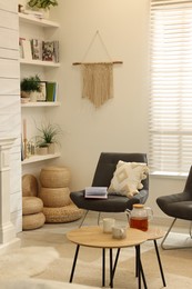Photo of Comfortable chairs near shelves with different decor in room. Interior design