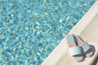 Photo of Stylish slippers near outdoor swimming pool on sunny day, space for text