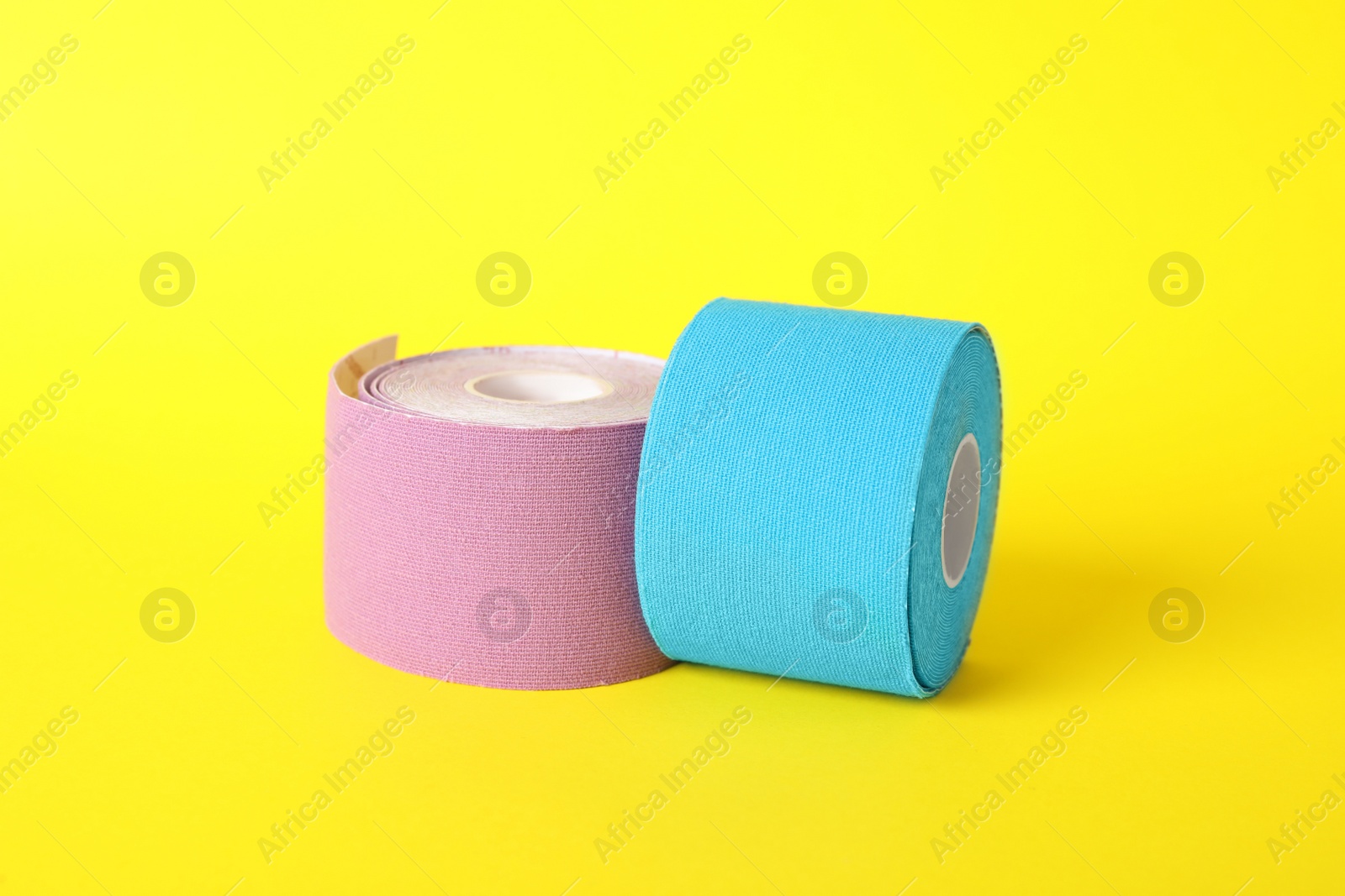 Photo of Bright kinesio tape in rolls on yellow background