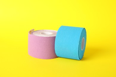 Photo of Bright kinesio tape in rolls on yellow background