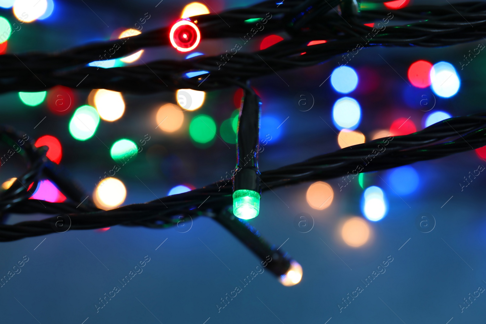 Photo of Beautiful Christmas lights on color background, closeup