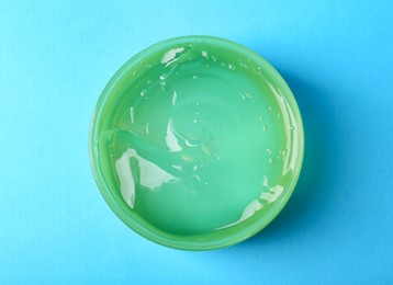 Photo of Aloe gel in jar on light blue background, top view