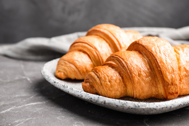 Photo of Tasty fresh croissants on brown marble table, closeup