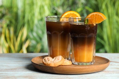 Photo of Tasty refreshing drink with coffee and orange juice on white wooden table against blurred background