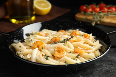 Delicious pasta with shrimps on black table, closeup