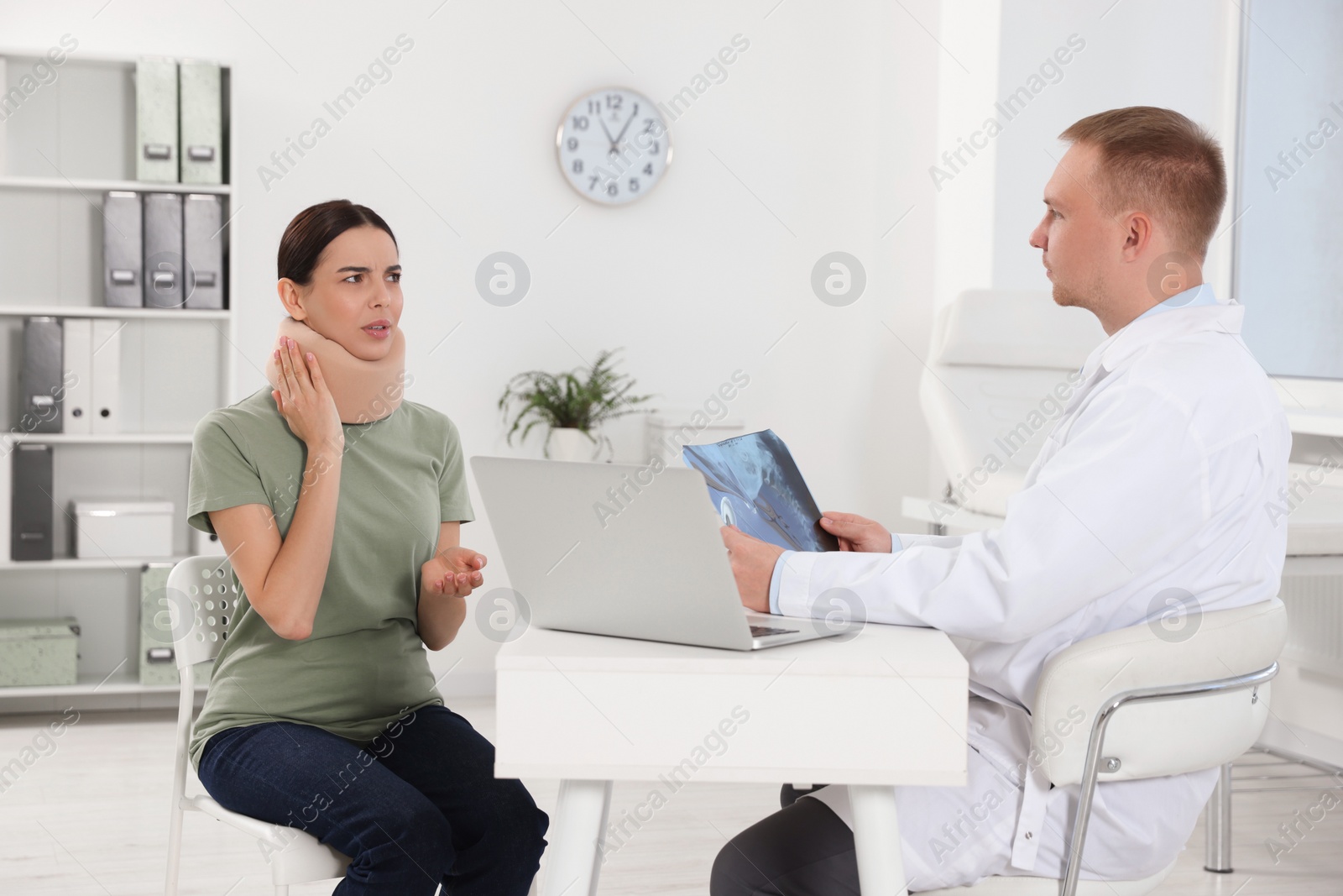 Photo of Doctor with neck MRI image consulting patient in clinic