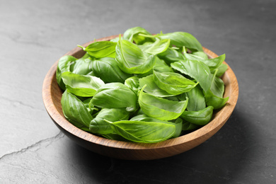 Photo of Fresh basil leaves in bowl on grey table