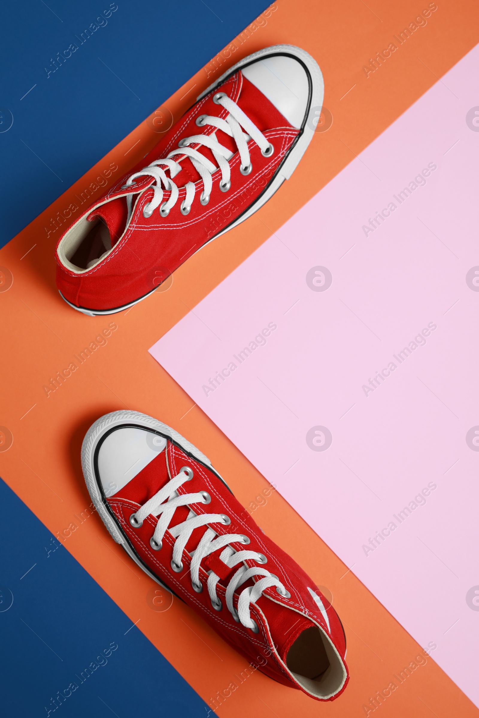 Photo of Pair of new stylish red sneakers on colorful background, flat lay