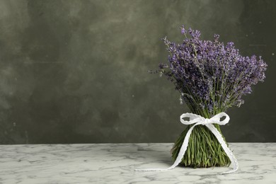 Photo of Beautiful lavender bouquet on white marble table against grey background. Space for text