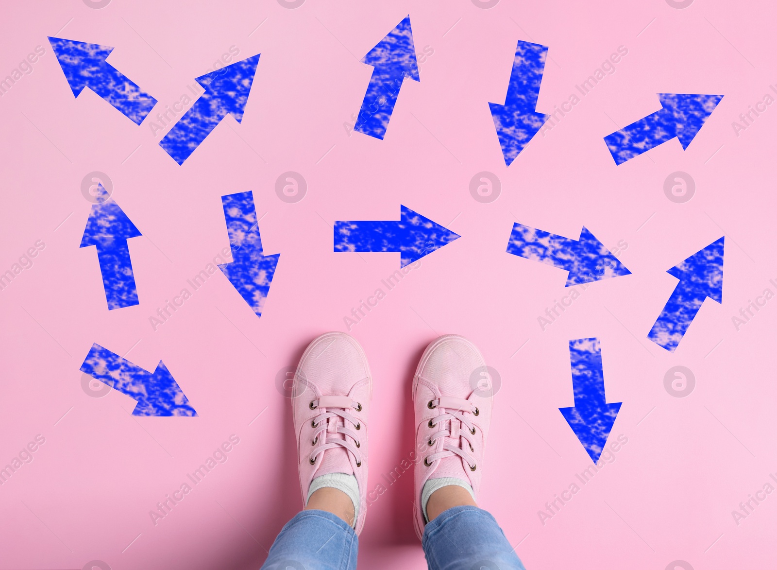 Image of Choosing future profession. Girl standing in front of drawn signs on pink background, top view. Arrows pointing in different directions symbolizing diversity of opportunities