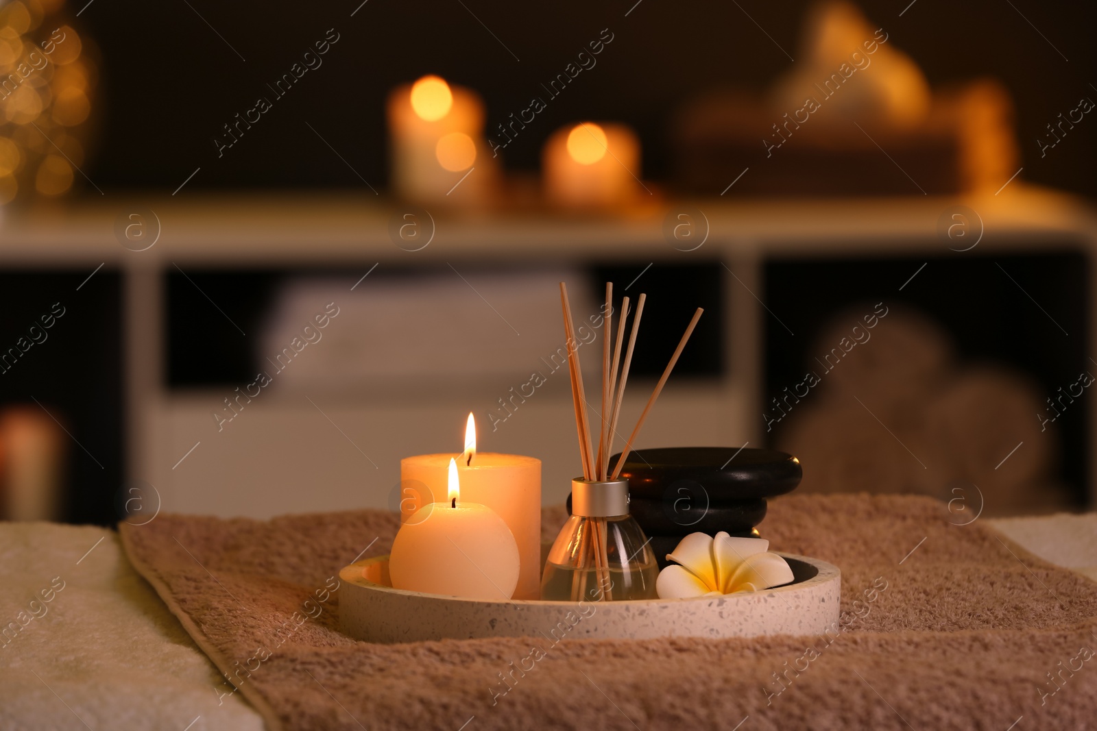 Photo of Burning candles and aromatic reed freshener on table in spa salon