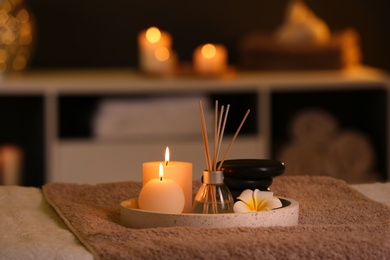 Photo of Burning candles and aromatic reed freshener on table in spa salon