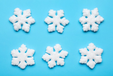 Beautiful decorative snowflakes on light blue background, flat lay