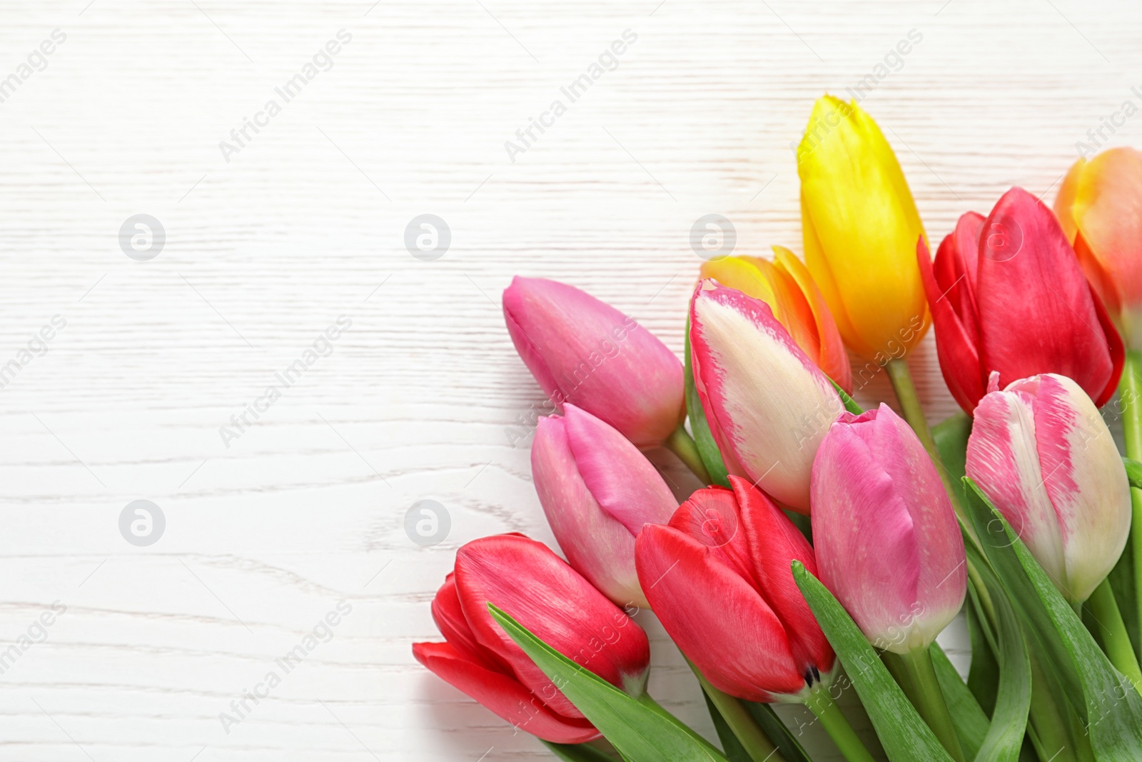 Photo of Beautiful tulips and space for text on wooden background, top view. Spring flowers