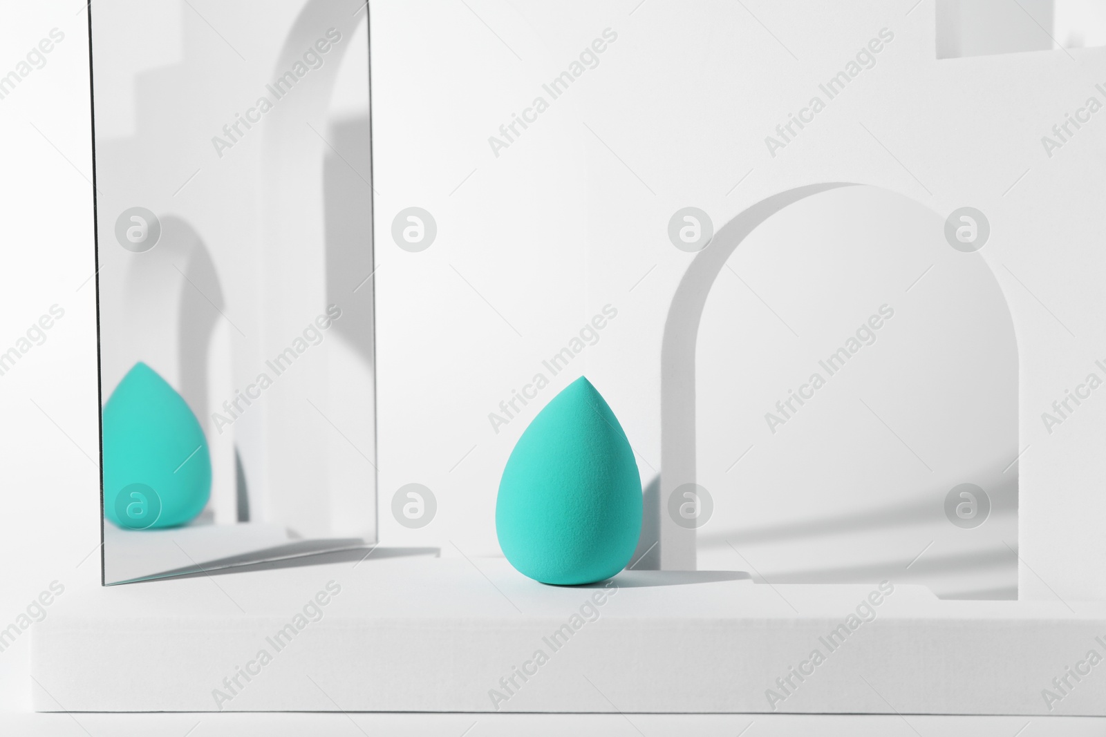 Photo of Stylish presentation of turquoise makeup sponge on white background