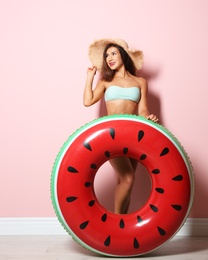 Beautiful young woman with inflatable ring near color wall