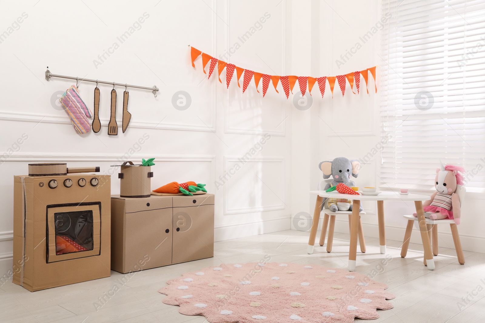 Photo of Toy cardboard kitchen with stove and utensils at home