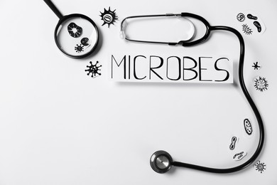 Photo of Card with word Microbes, pictures, magnifying glass and stethoscope on white background, flat lay. Space for text