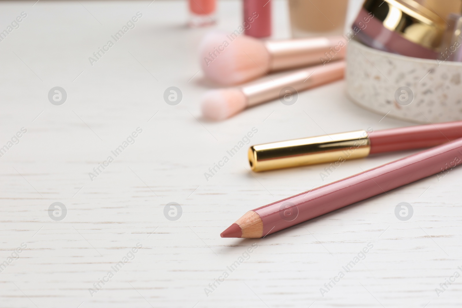 Photo of Lip pencils on white wooden table, closeup view with space for text. Cosmetic product
