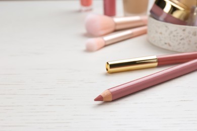 Photo of Lip pencils on white wooden table, closeup view with space for text. Cosmetic product