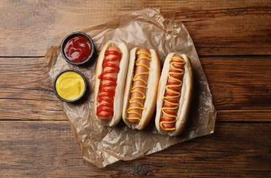 Delicious hot dogs with mustard and ketchup on wooden table, top view