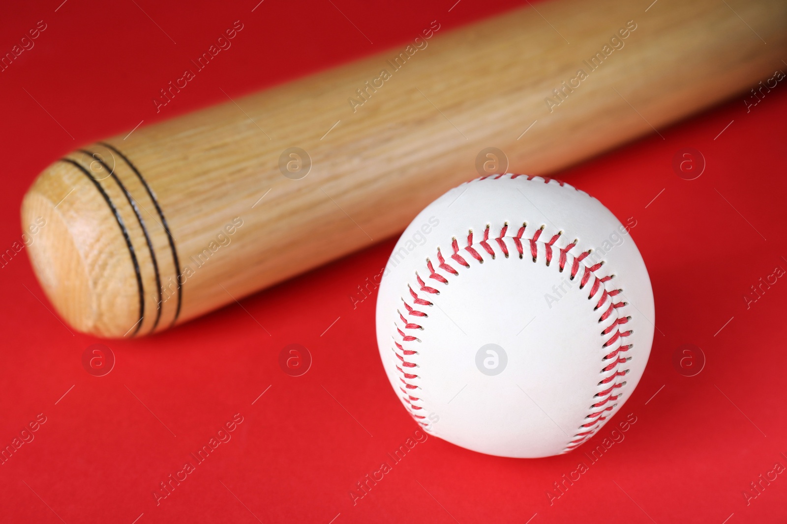 Photo of Wooden baseball bat and ball on red background. Sports equipment