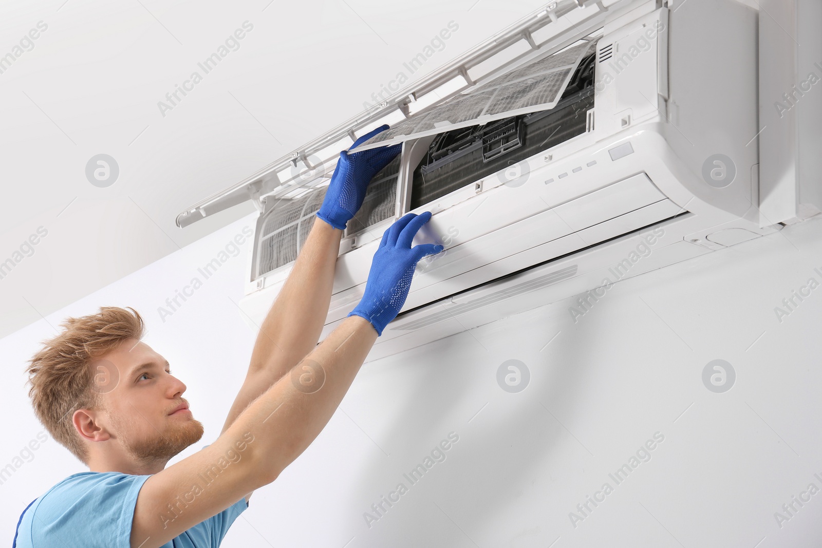 Photo of Professional technician maintaining modern air conditioner indoors