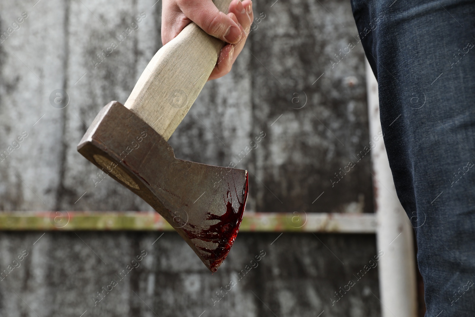 Photo of Man holding bloody axe outdoors, closeup view