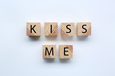 Photo of Wooden cubes with phrase Kiss Me on white background, flat lay