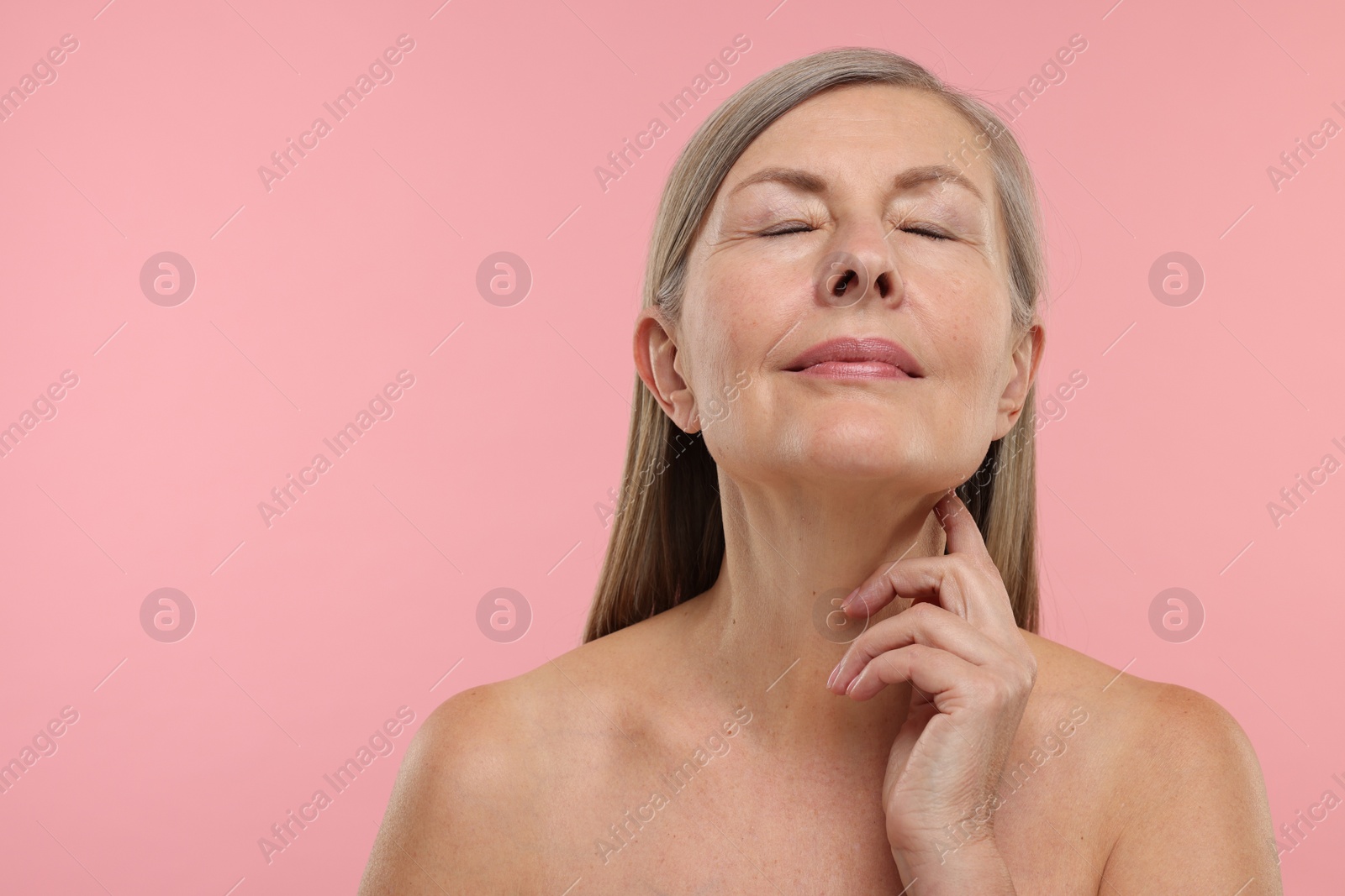 Photo of Beautiful woman touching her neck on pink background, space for text