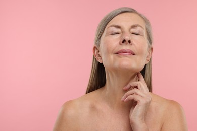 Beautiful woman touching her neck on pink background, space for text