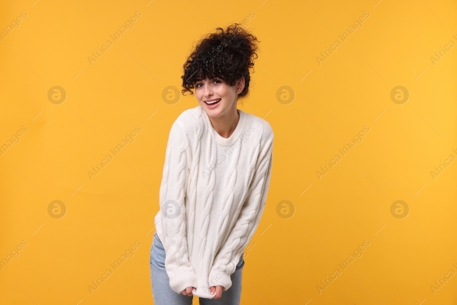 Photo of Happy young woman in stylish white sweater on yellow background