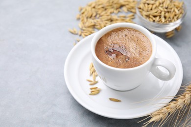 Cup of barley coffee, grains and spike on gray table, closeup. Space for text