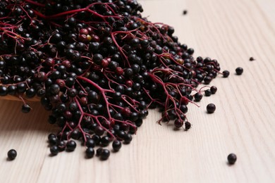 Photo of Tasty elderberries (Sambucus) on wooden table, closeup