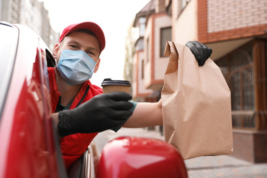 Courier in protective mask and gloves giving orders out of car window outdoors. Delivery service during coronavirus quarantine