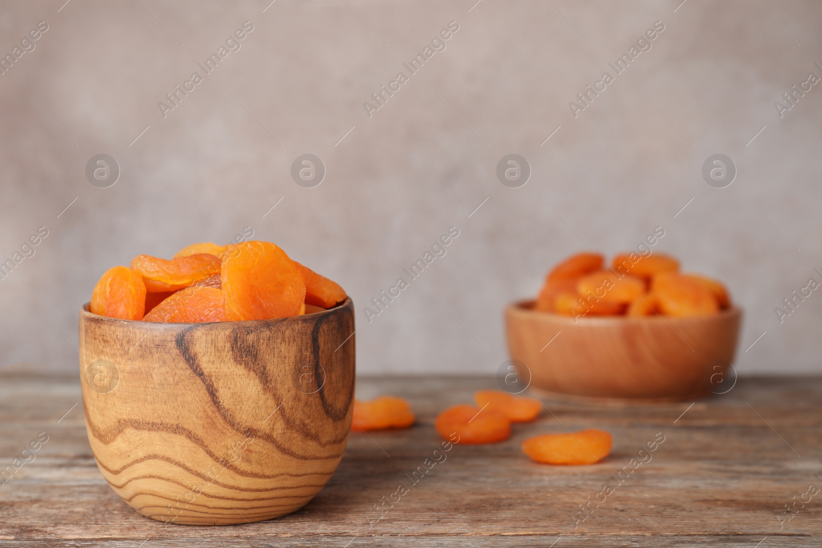 Photo of Bowl with apricots on wooden table, space for text. Dried fruit as healthy food