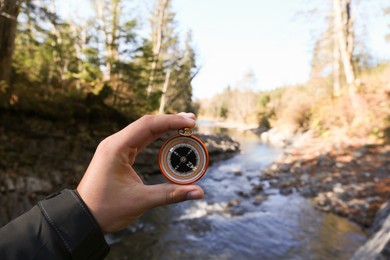 Photo of Man using compass near mountain river, closeup