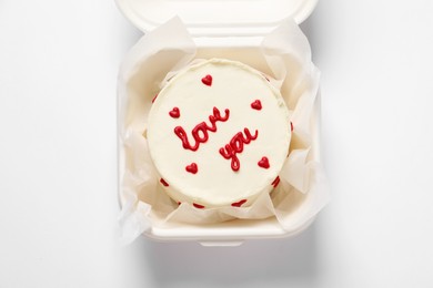 Photo of Bento cake with Love You text in takeaway box on white table, top view. St. Valentine's day surprise