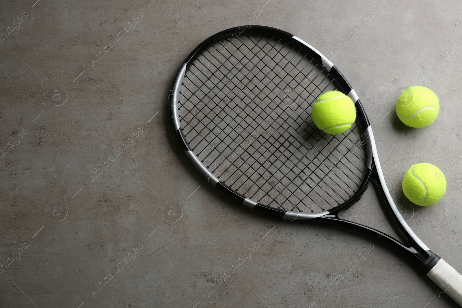 Photo of Tennis racket and balls on grey table, flat lay. Space for text