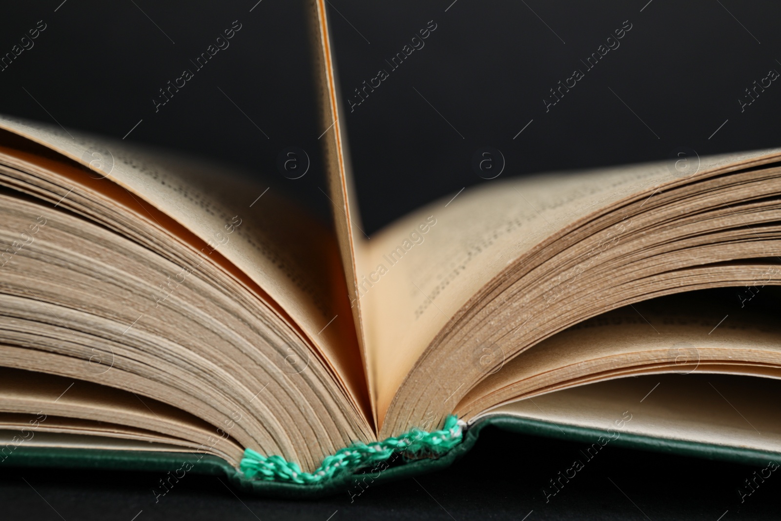 Photo of Closeup view of open book on black background